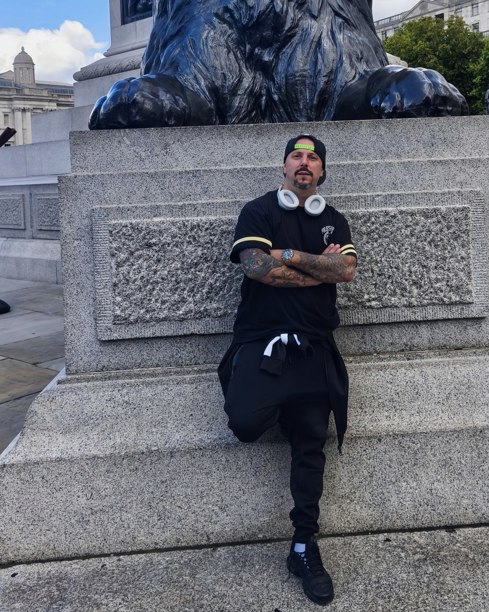 Retrato de FUNESMA79, brazos cruzados, junto a uno de los leones de Trafalgar Square