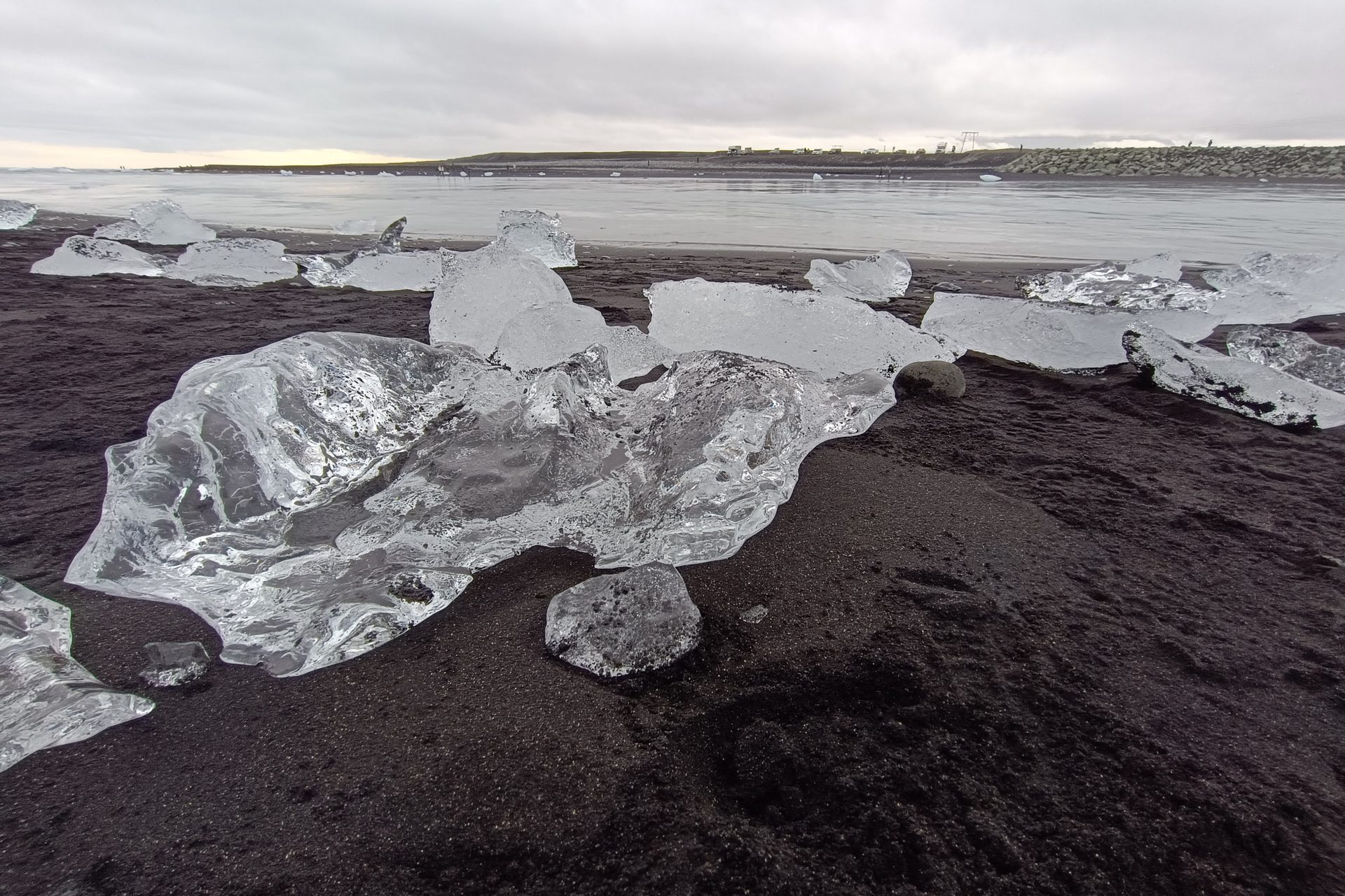 Bloques de hielo transparente varados sobre arena volcánica negra, en primer plano