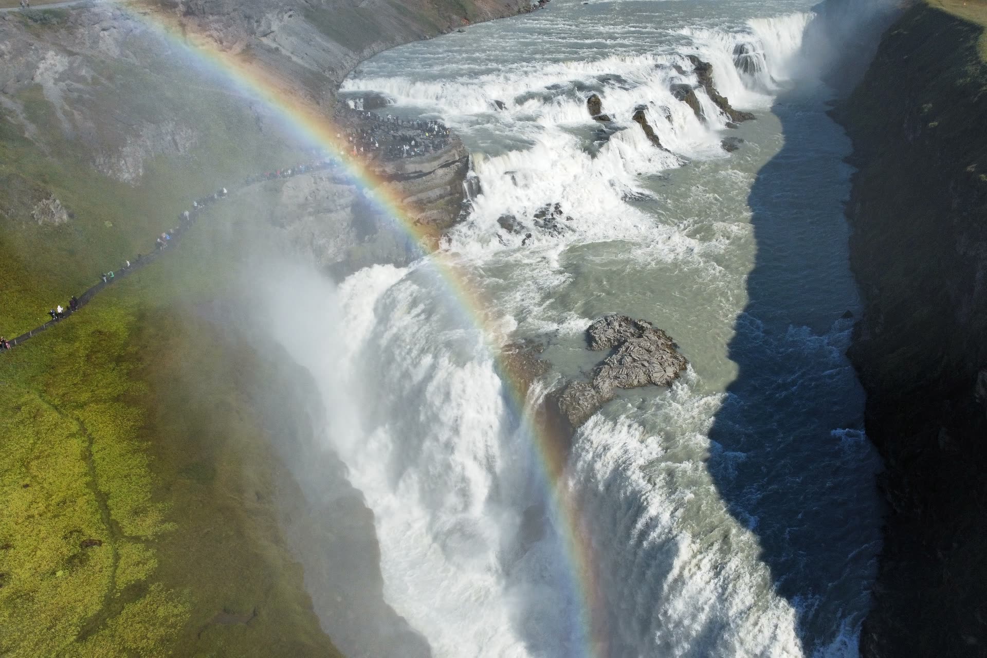 Cascada islandesa vista desde el aire, con un arcoíris cruzando la bruma
